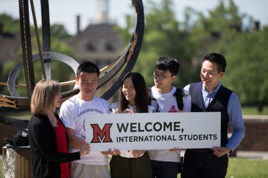 students and staff holding a sign that says "welcome, international students)